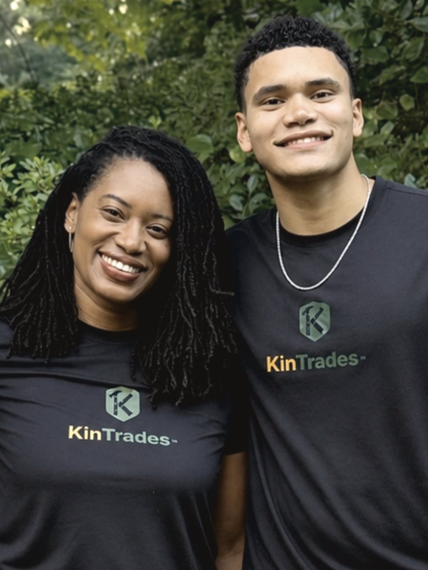 A KinTrades intern and the founder outdoors, both wearing KinTrades shirts.