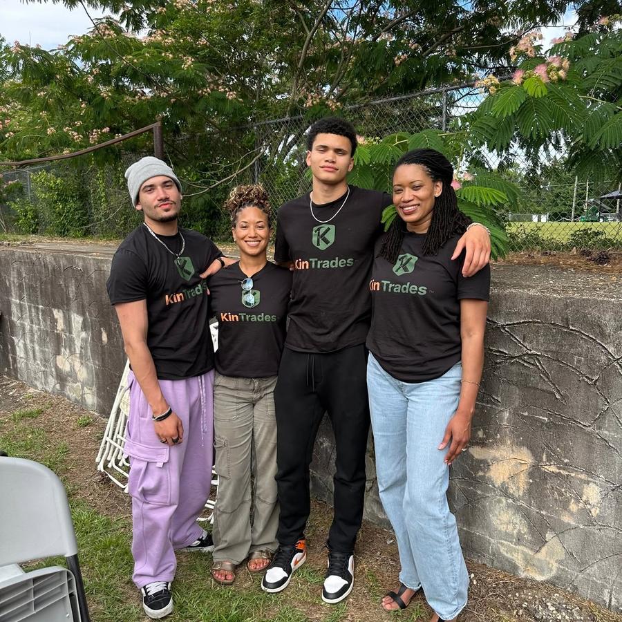 Four members of the KinTrades team outdoors, wearing KinTrades shirts.